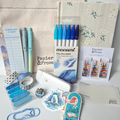 Stationery items including pens, notebooks, and stationery supplies on a textured surface.